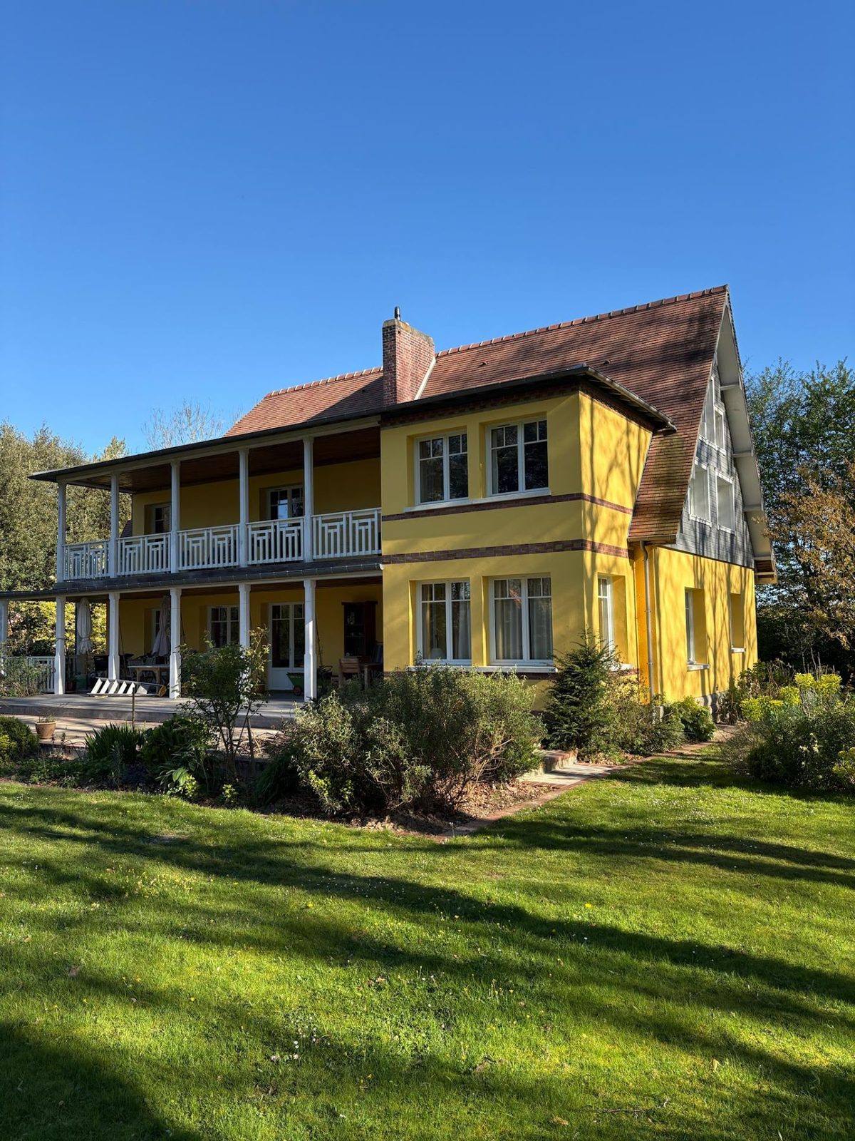Grande maison jaune à balcons après travaux